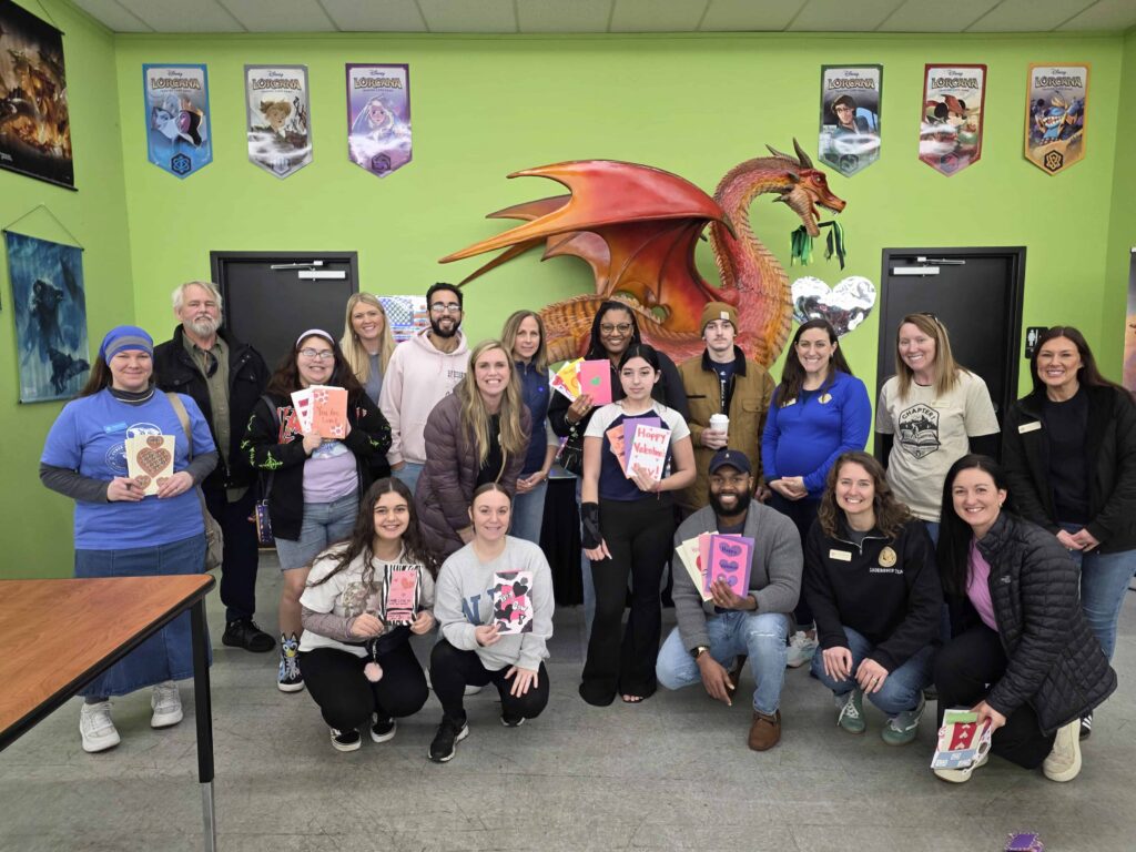 Группа людей, улыбающихся на фоне зеленой стены